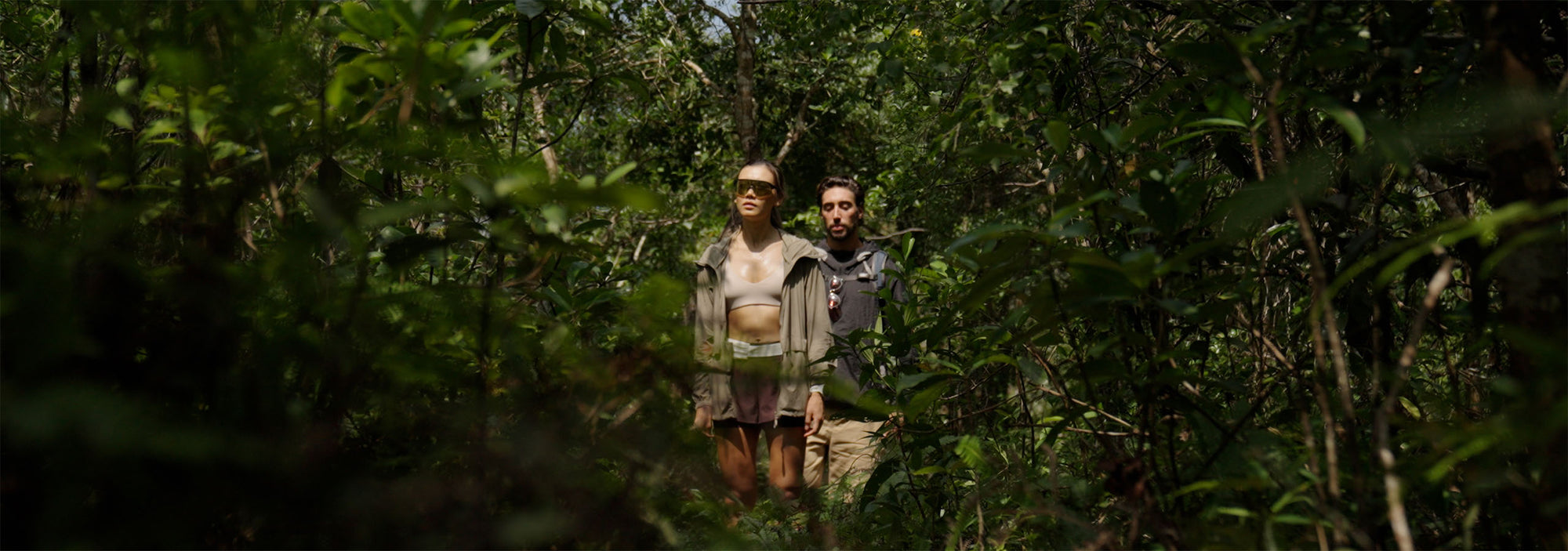 Two people walking through a dense forest