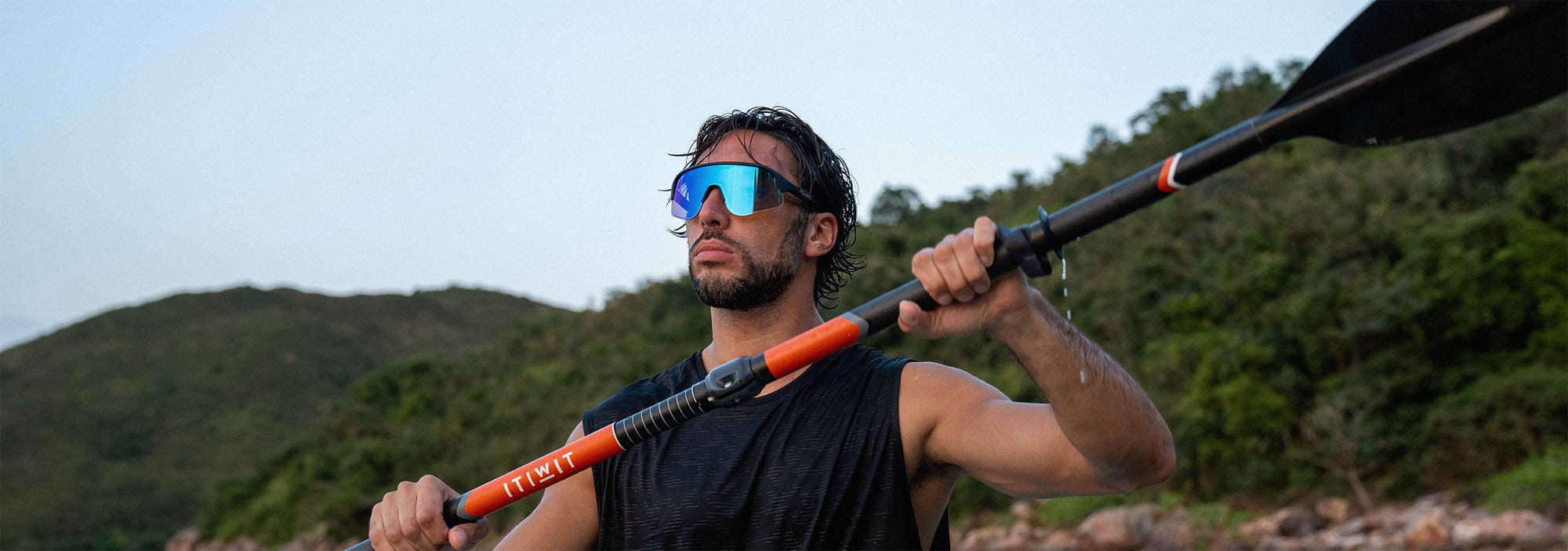 Man holding a paddle with mountains in the background