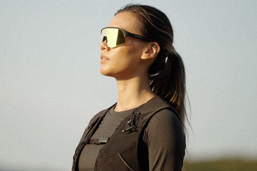 Woman wearing gold sunglasses against a clear sky