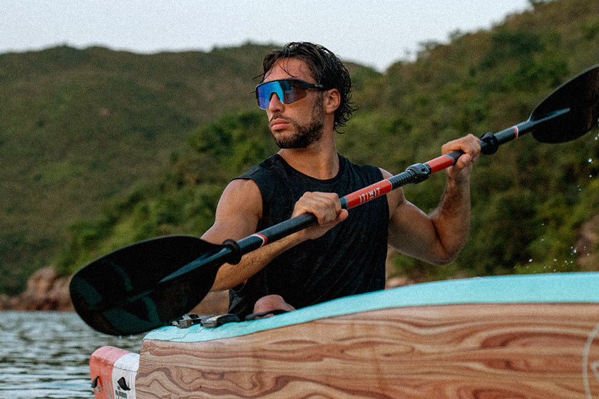 Man holding a paddle on a kayak with a scenic background